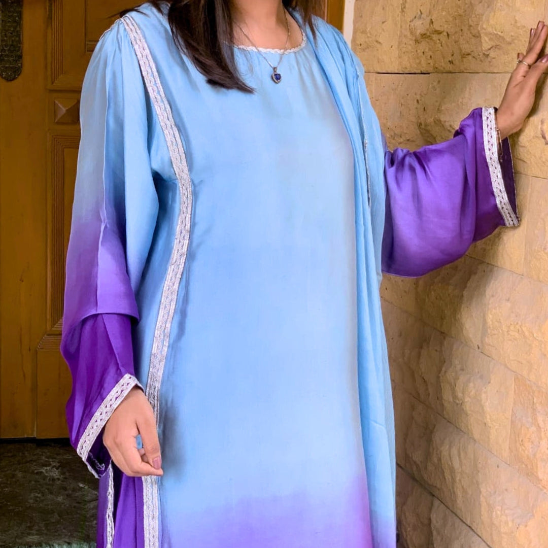 Person wearing a light blue and purple dress with a wooden door and wall in the background