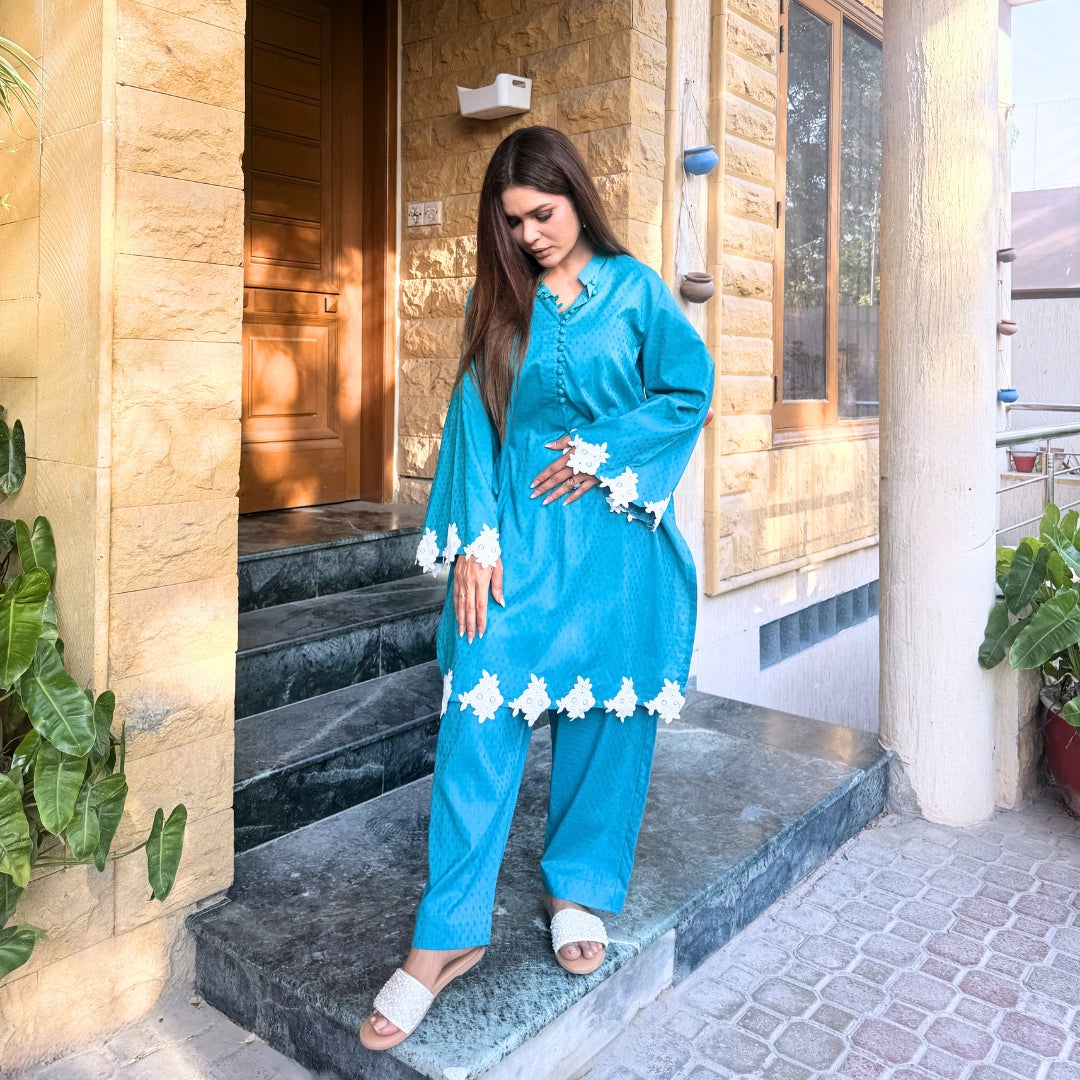Woman in a blue traditional outfit standing on steps outside a building.
