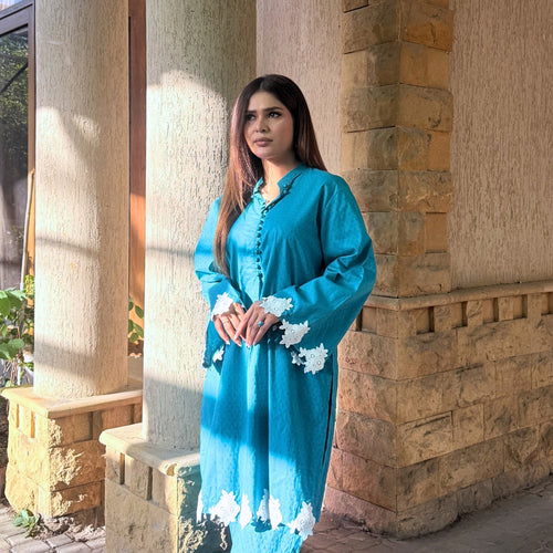 Woman in a blue dress standing against a stone wall