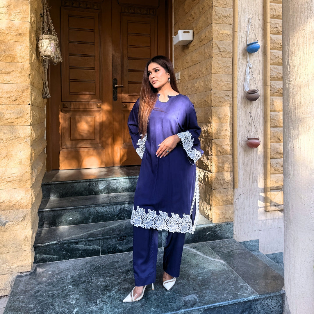 Woman in a blue outfit standing on stone steps outside a building.