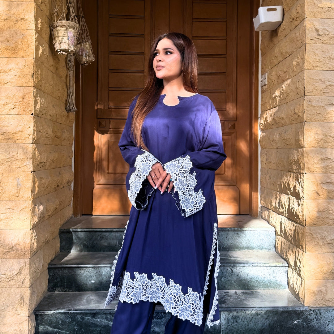 Woman in a blue dress with lace details standing on stone steps.