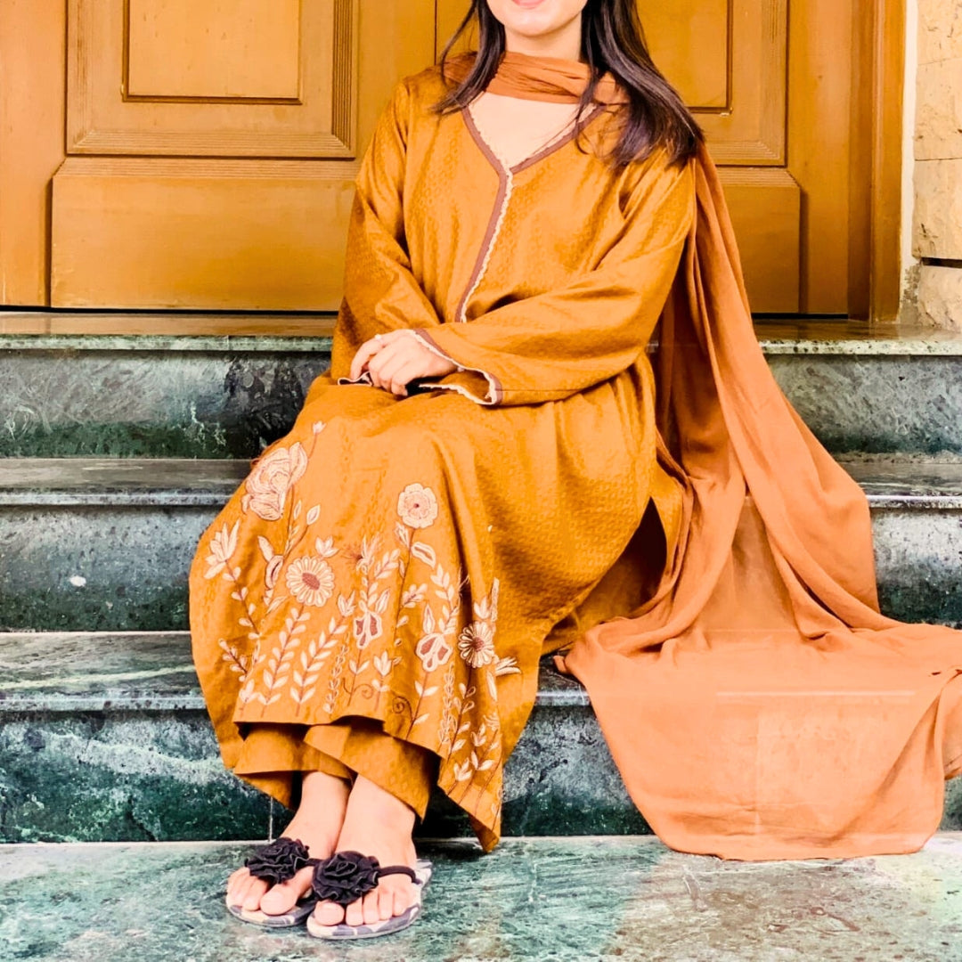 Person wearing a mustard yellow dress and sit on stone stairs.