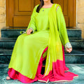 Person wearing a bright green and pink traditional outfit sitting on steps.