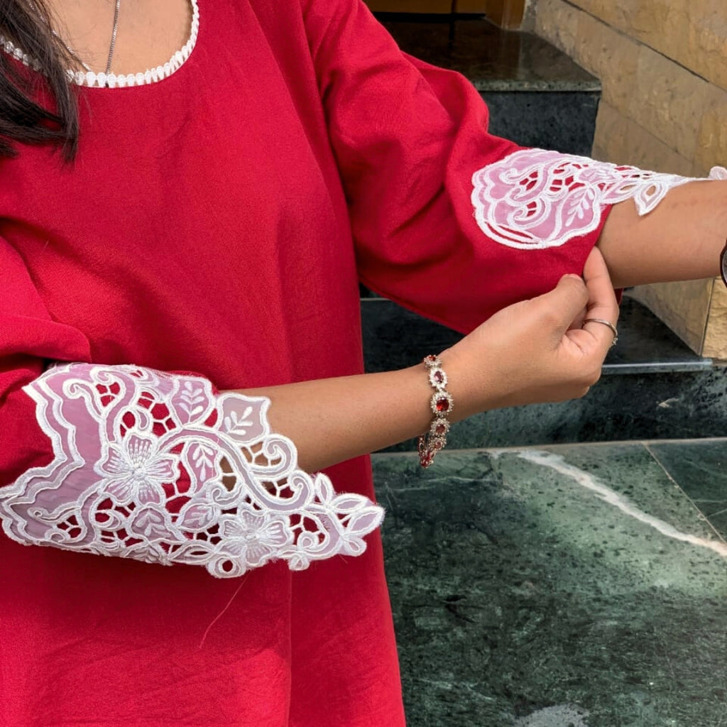 Person wearing a red outfit with white lace sleeves, standing on a marble floor.