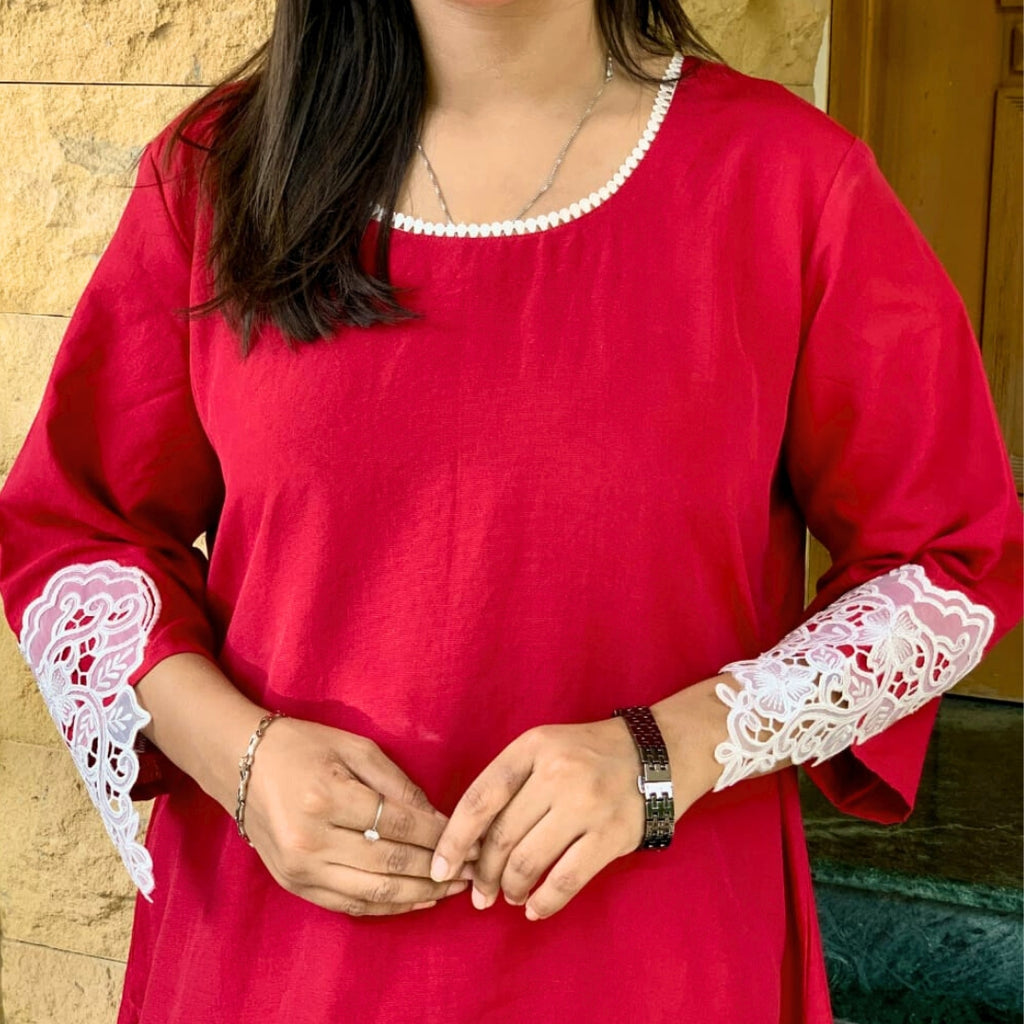 Red kurta with white lace sleeves worn by a person, against a neutral background