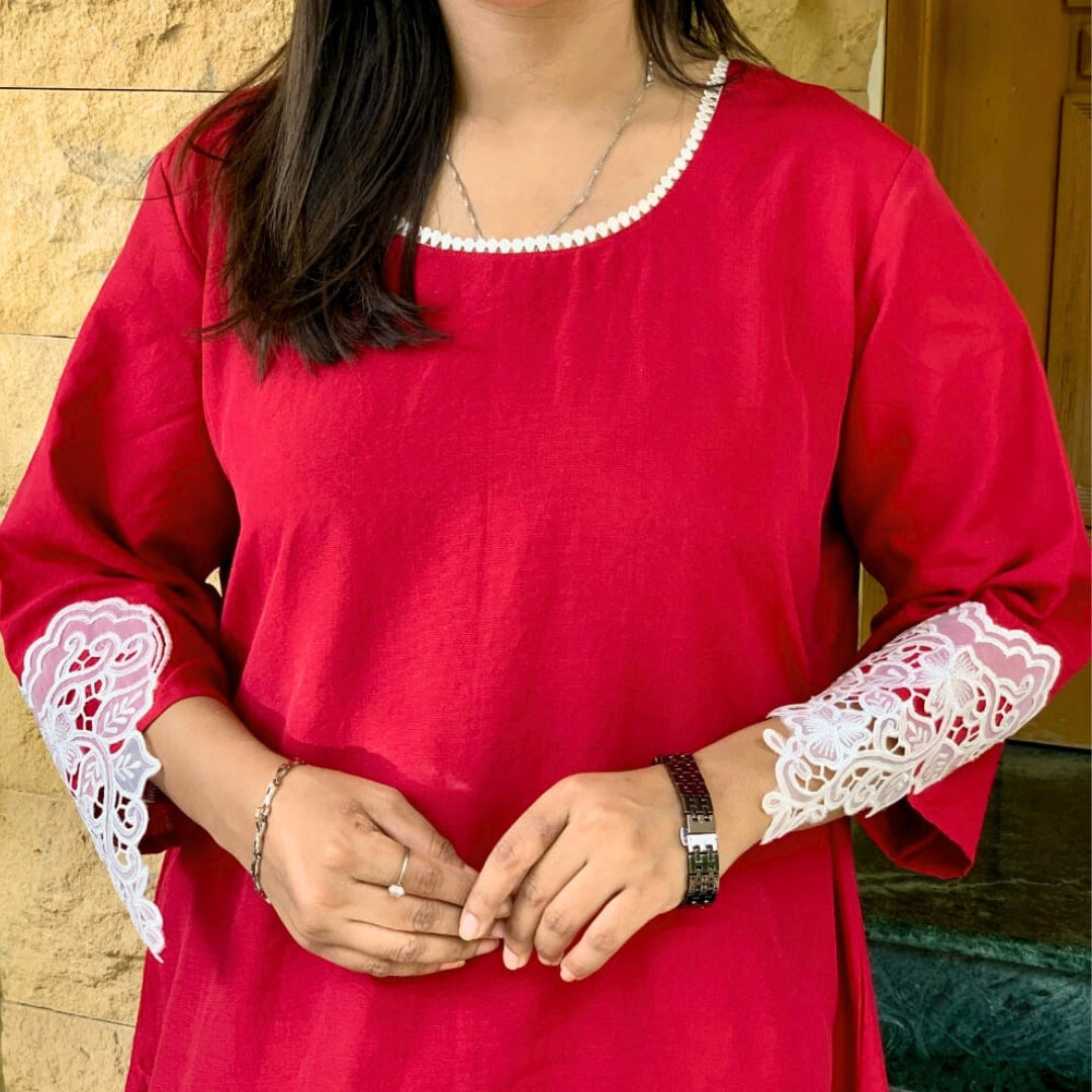 Red kurta with white lace sleeves worn by a person, against a neutral background
